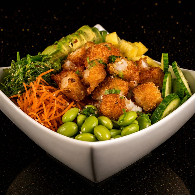 A poke bowl filled with crispy shrimp, avocado, seaweed, carrots, edamame, cucumber, and pineapple.