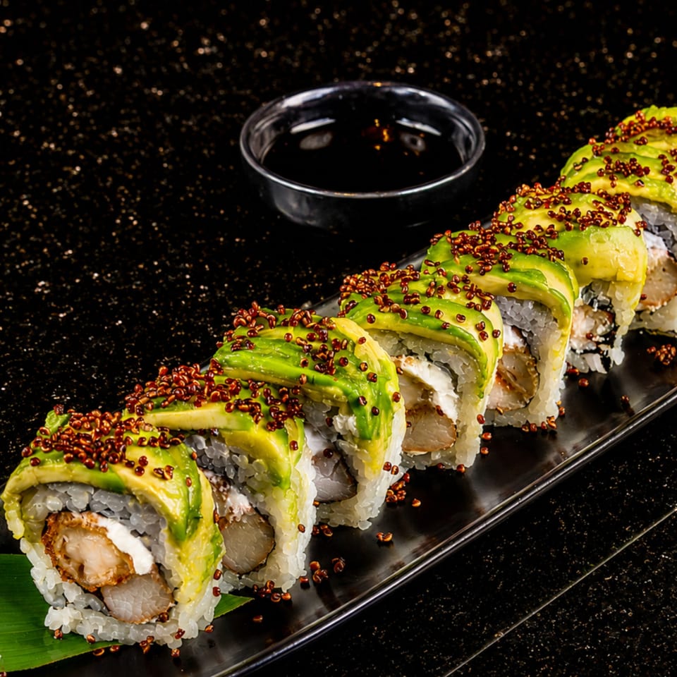Avocado sushi rolls with crispy shrimp, cream cheese, and quinoa on a black plate with soy sauce.